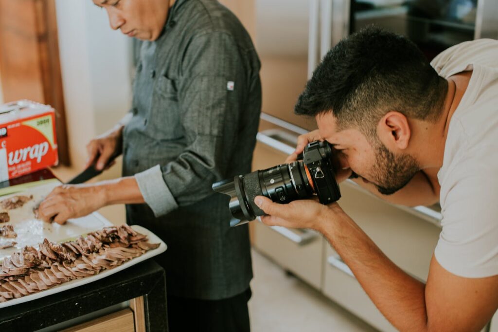 pexels photo 11157604 A photographer captures a chef slicing meat on a tray in a kitchen setting.