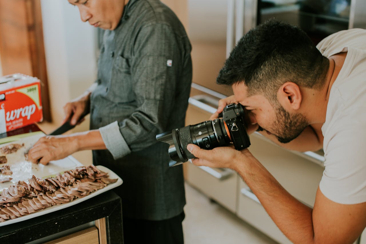 who-we-are-01 A photographer captures a chef slicing meat on a tray in a kitchen setting.